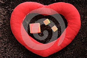 Red big love shape on a dark brown background, with three small gift boxes inside the heart. Valentine day and Christmas tree.