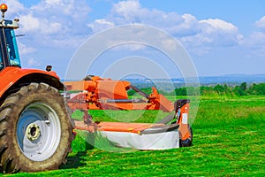 Red big mower mows the grass in the field. Preparation of silage for the winter.