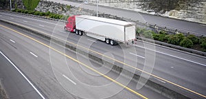 Red big rig long haul semi truck with dry van semi trailer running on divided wide highway photo