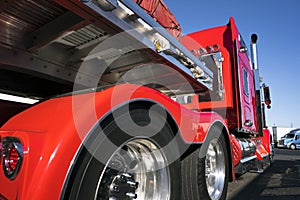 Red big rig semi truck with alumnum flat bed semi trailer standing for rest on truck stop