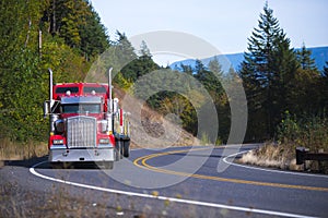 Red big rig Semi Truck with trailer winding road