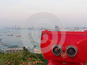 Red binocular on Pattaya beach showing explore and discover new place in tourism industry