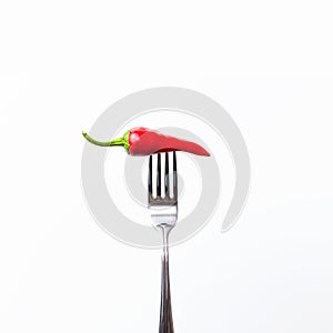 Red bitter chili pepper on the fork on white isolated background. Creative Food concept