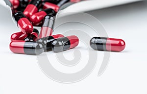 Red-black antibiotic capsule pills with blur drug tray on white table. Antibiotic drug smart use. Prescription medicine. Pharmacy