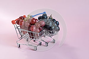 Red and black grapes in grocery baskets.