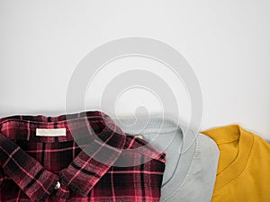 Red-black plaid shirt,grey T shirt and yellow T shirt folded on white background
