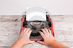 Red and black retro typewriter with white blank paper sheet on the wooden table table