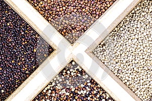 Red, black and white and mixed quinoa seeds on white background.