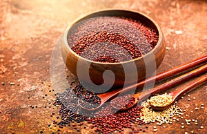 Red, black and white quinoa grains in a wooden spoon. Healthy food in a bowl. White, red and black seeds - Chenopodium q