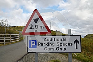 Red, black and white warning triangle in UK for two metre height restriction. Sign Additional Parking Spaces Cars Only.