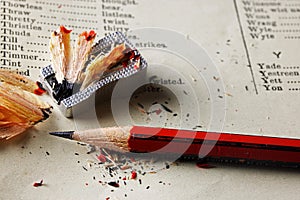 RED AND BLACK WOODEN PENCIL WITH SHARPENER AND SHAVINGS