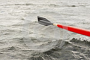 Red and black wooden paddle rowing boat in the lake.