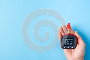 Red blood drop with Blood glucose test strips and Glucose meter in man hand on blue background