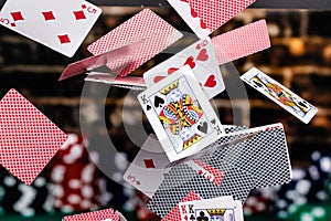 Red and Blue backed Playing cards cascading in front of a background of stacked poker chips