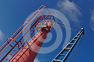 Red and blue boat crane with blue sky