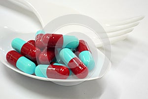 Red and blue capsules on plastic spoon fork