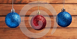 Red and blue Christmas balls hanging on strings on wooden background
