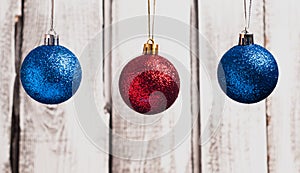 Red and blue Christmas balls hanging on strings on wooden background