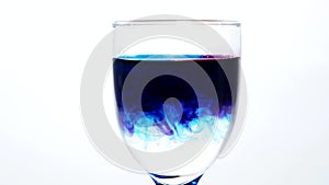 Red and blue colors paint cloud in glass of water on a white background
