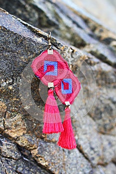 Red and blue earrings from threads hangs on a stones. Handmade jewelry