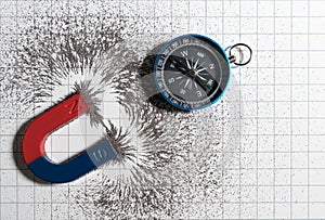Red and blue horseshoe magnet or physics magnetic and compass with iron powder magnetic field on white paper graph background.