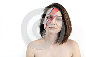 Red and blue lightning bolt on her beautiful face. Beautiful girl with original make-up on a white background. Studio