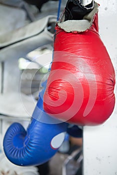 Red and Blue Muay Thai boxing gloves hanging on Corner of boxin