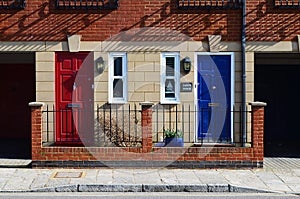 Red and blue neighbor doors in brick walled crew house