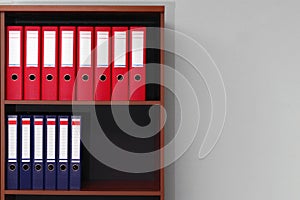 Red and blue office ring binder folders on shelves with copy space