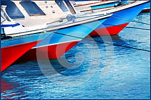 Red and blue old fishing boats in the seaport. Colored reflections in the water. Sea background.