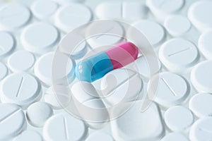 Red and blue pill lying among white drugs