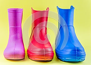 Red blue and pink rubber boots EVA on a yellow background