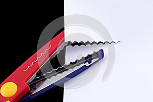 Red and blue pinking shears cutting a white piece of paper