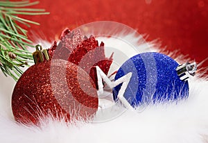 Red, blue shiny ball and flower with star with fir branch on fur from behind blurred background. Christmas, New Year