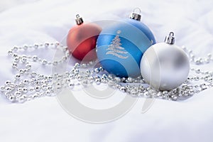 Red, blue and silver Christmas baubles on white background