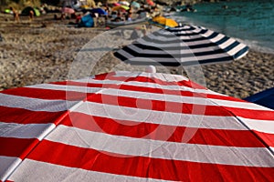 Red, blue and white sun umbrella for sunbathing and protection of sun rays, closeup. Colorful parasol beach umbrella.