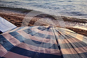 Red, blue and white sun umbrella for sunbathing and protection of sun rays, closeup. Colorful parasol beach umbrella.