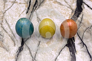 Red, blue, yellow Easter eggs. Three multicolored handmade easter eggs on a blue wooden background. Square. Close-up. photo