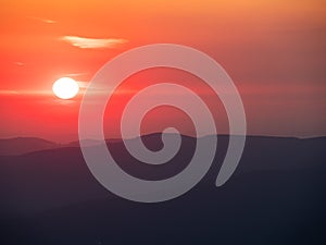 Red blurry sunrise time over Karkonosze mountains. Mist over the range. Poland