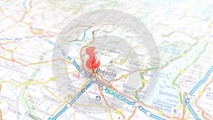 A red board pin stuck in Brescia on a map of Italy