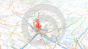 A red board pin stuck in Brescia on a map of Italy photo