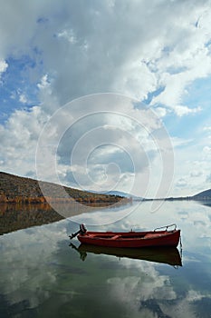 Red boat in the calm water of the lake