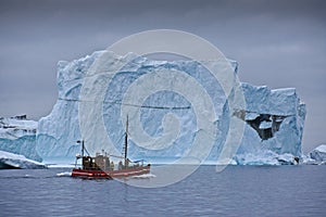 Red boat among icebergs in Disko Bay, West Greenland