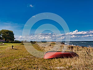 Red boat is lying on a meadow on the beach