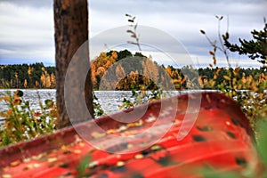 Red boat lying in shrubbery at a lake shore in northern Sweden
