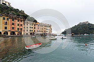 Red boat on water with Colorful houses at square of Portofino.