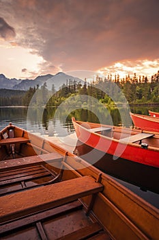 Red boats on Lake Strbske pleso. Morning view of the High Tatras National Park, Slovakia, Europe.