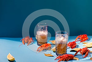 Red boiled Crawfish and beer glasses on a blue background. Trendy bi-colored minimalist still life