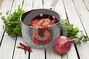 Red boiled crawfish with onion and parsley on the white wooden background. Rustic style. Seafood. Steamed crayfish.