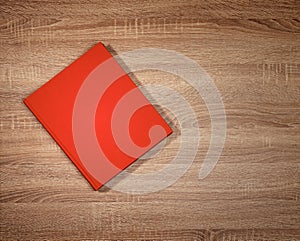 Red book on dark brown wooden table.